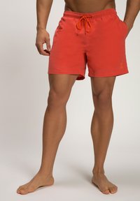 Rode zwembroek met een elastische tailleband en een oranje trekkoord. Voorzien van zijzakken en een klein logo op het linkerbeen.
