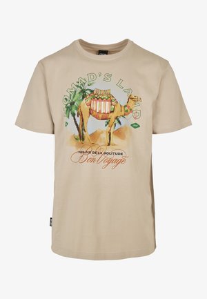 Camiseta beige con un gráfico colorido de un camello, palmeras y texto que dice "Tierra de Nómadas", "Paraíso de la soledad" y "Buen viaje".