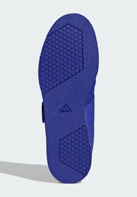 Podeszwa buta z heksagonalnym wzorem i teksturowanym uchwytem. Przeważająco purpurowy materiał o gładkim wykończeniu z logo marki w pobliżu pięty.