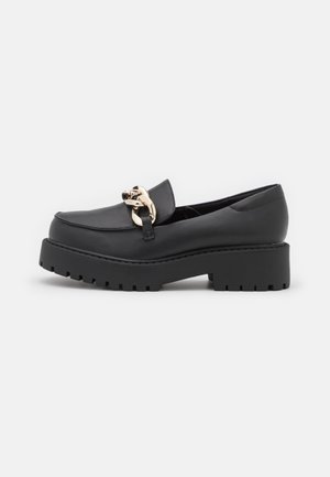Black leather loafers with a chunky platform sole and decorative gold link hardware on the upper. Smooth texture, rounded toe design.