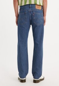 Blå denimjeans med rak passform, med två bakfickor, en läderlogotyp och synliga söms detaljer.