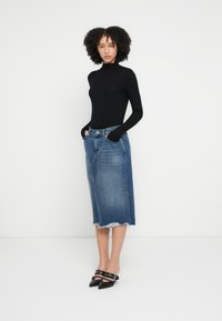 Fekete garbófelső, szakadt szegélyű koptatott kék színű farmer midi szoknya, ötpocketes kialakítás, valamint fekete, pántos részletekkel ellátott hegyes orrú mules cipő.