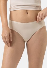 Beige katoenen slip met een gladde afwerking, middelhoge taille en zachte elastische band, weergegeven tegen een neutrale achtergrond.
