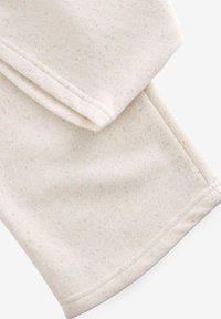 Világos krémszínű szövet többszínű pöttyökkel. Puha textúrájú, sima varrással a szélén.