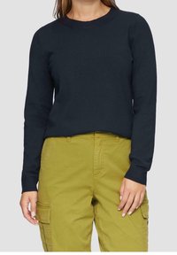 Maglione a maniche lunghe blu navy con design aderente, dotato di scollatura rotonda e polsini a coste, abbinato a pantaloni cargo verde oliva.