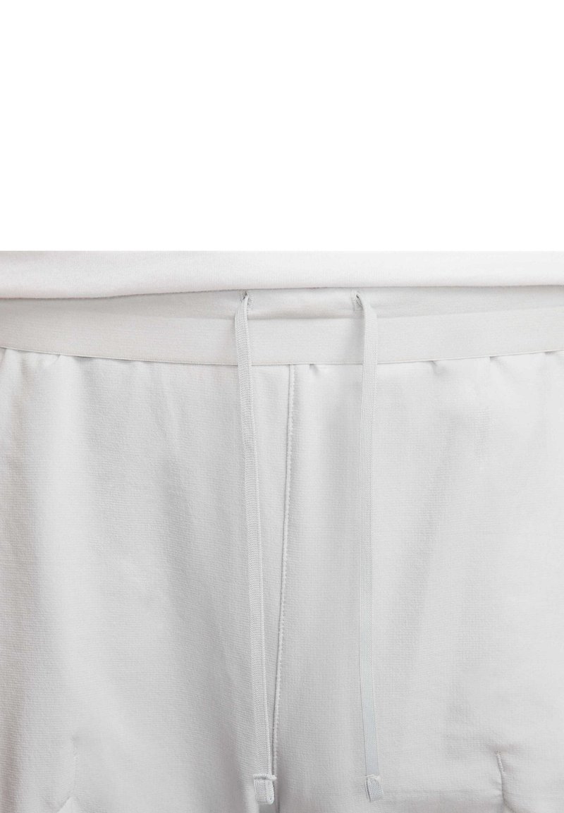 Pantalons de survêtement gris clair avec taille élastique et cordon de serrage, texture lisse. Design simple et fonctionnel sans motifs supplémentaires.