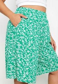 Zelené květinové kraťasy z měkkého materiálu s vysokým pasem, bočními kapsami a vzorem malých bílých květinek.