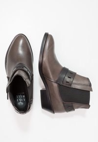 Szare skórzane botki za kostkę z ostrym noskiem, elastycznymi panelami bocznymi i grubym obcasem. Udekorowane czarnym paskiem na kostce.