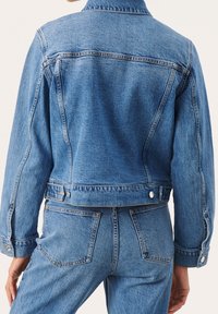 Jeansjacka i ljusblått med en klassisk design, knappdetaljer och en något kortad passform med synlig sömnad och fickor.