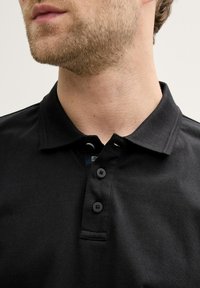 Sort polo skjorte med krave, tre-knaps lukning og korte ærmer. Lavet af bomuld, med en glat tekstur og uden mønstre.
