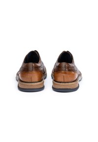 Scarpe in pelle marrone con una superficie liscia, caratterizzate da dettagli cuciti e una suola intermedia a contrasto. Tacco arrotondato e accenti elastici laterali.