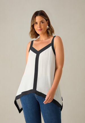 Witte mouwloze bloes met zwarte afwerking, V-hals ontwerp, vloeiende stof en asymmetrische zoom, gecombineerd met blauwe jeans. Zachte textuur.