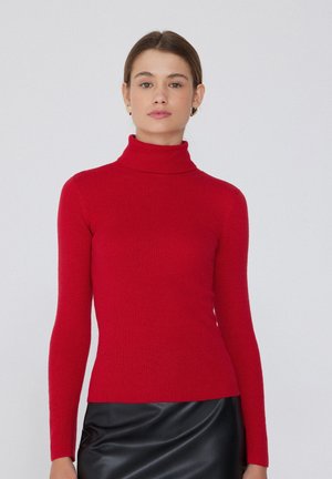 Červený rolák z ribbed látky, s dlouhými rukávy a přiléhavým střihem, v kombinaci s černou koženou sukní.