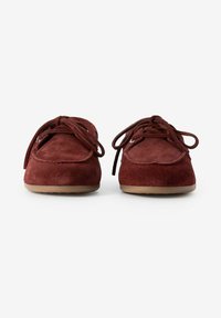 Rote Wildlederschuhe mit runden Zehen, flachen Sohlen und Schnürdesign. Besitzen eine glatte Textur und minimalistische Stickdetails.