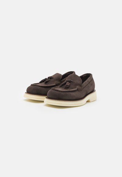 Loafers din suede maron cu ciucuri decorativi, vârf rotund și talpă din cauciuc de culoare deschisă. Textură netedă cu accente cusute.