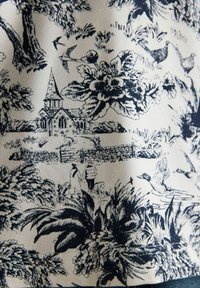 Schwarz-weißer Toile-Stoffmuster, das eine Kirche, Vögel, Enten, Pflanzen und zwei Personen zeigt, die auf einem Weg in einer ländlichen Szene spazieren.