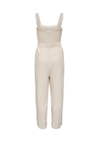 Tuta beige senza maniche con corpetto arricciato, spalline larghe, vita con cintura e pantaloni larghi alla caviglia su sfondo bianco.