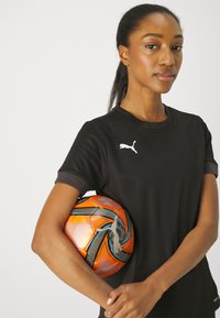 Black athletic shirt with short sleeves, featuring a white Puma logo. Holding an orange and black patterned soccer ball. Smooth texture.