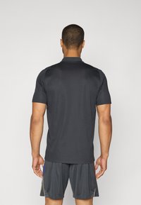 Donkergrijze polo met korte mouwen, een rechte zoom en subtiele glans, met een klassieke kraag en een minimalistisch ontwerp.