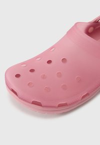 Pink foam clogs featuring ventilation holes, rounded toe, textured surface, and a back strap for secure fit. Lightweight and flexible design.