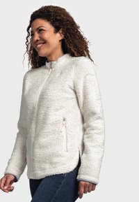 Veste en polaire blanche, dotée d'une fermeture éclair sur le devant, d'un col montant et de deux poches latérales à fermeture éclair. Texture douce avec un ourlet arrondi.
