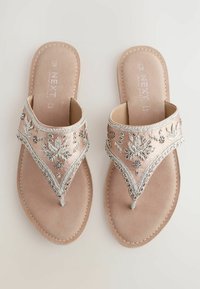 Dekorerade platta sandaler med ett mjukt rosa satinband med silverfärgad blombroderi, en mellanrumdesign och en beige vadderad sula.