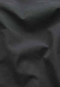 Melns audums ar gludu, matētu virsmu, kurā redzamas smalkas krokas un gaismas nokrāsas, norādot uz vieglu materiālu.