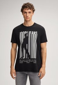 Zwarte katoenen T-shirt met witte grafische tekst en silhouetontwerp, met korte mouwen en een ronde hals.