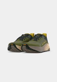 Baskets de sport vertes et noires avec une tige en maille texturée, accents jaunes et semelle Vibram pour une meilleure traction. Présente un design rembourré et sculpté.