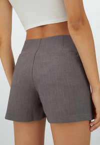 Grijze op maat gemaakte shorts van een gestructureerde stof, met een middelhoge taille, twee achterzakken en strakke lijnen.