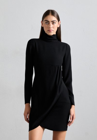 Robe noire à manches longues avec un col montant, un corsage ajusté, un devant drapé et une longueur au-dessus du genou. Tissu doux avec une texture lisse.