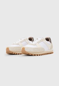 Sneakers bianchi con accenti in camoscio beige, suola in gomma texturizzata e design con lacci. Presentano una tomaia in tessuto liscio e un sottile dettaglio del logo.