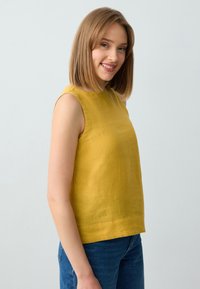 Blusa senza maniche gialla con vestibilità morbida, realizzata in tessuto leggero. Texture liscia, orlo dritto e senza motivi o dettagli visibili.