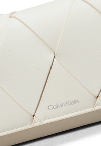 Weißes, strukturiertes synthetisches Leder-Clutch mit gequiltetem Diamantdesign und dezentem Calvin Klein Logo. Verfügt über eine glatte, matte Oberfläche.