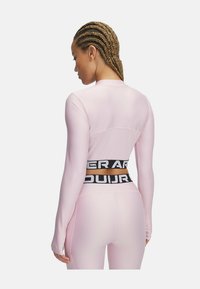 Pink long-sleeve shirt with a fitted design, featuring black branded elastic waistband. Smooth texture, designed for athletic wear.