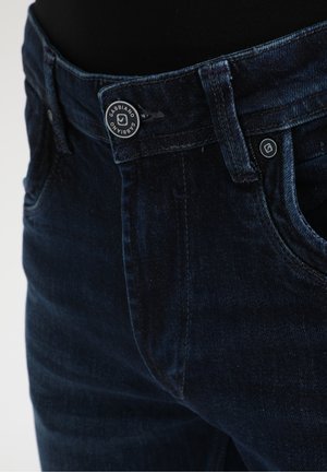Dunkelblaue Jeans aus Denim mit Knopfverschluss, ausgestattet mit fünf Taschen, Gürtelschlaufen und einem Stoffetikett am Bund. Glatte Textur.