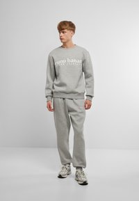 Gray sweatshirt and sweatpants set, featuring a crew neck and elastic cuffs. The sweatshirt has white text printed on the front.