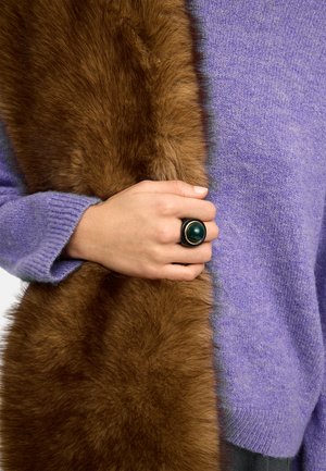 Dłoń z ciemnozielonym efektownym pierścieniem trzymającym brązowy futrzany szal zarzucony na lawendowy, dziergany sweter.