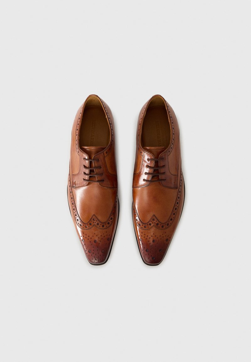 Brązowe skórzane buty wizytowe z wąskim noskiem, detalami w stylu brogue i pięcioma otworami na sznurowadła. Gładkie wykończenie z nieco ciemniejszą strefą na nosku.