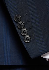Mankiet granatowego garnituru z teksturowanej tkaniny z subtelnymi paskami. Cztery czarne guziki o okrągłym wzorze z grawerem marki.