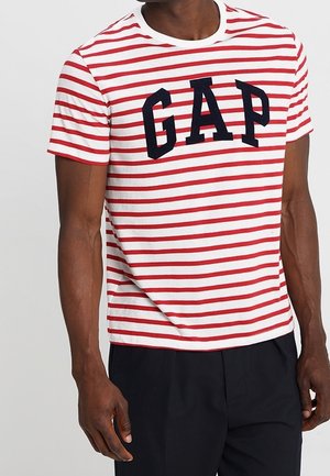 Rot-weiß gestreiftes T-Shirt aus Baumwolle mit Rundhalsausschnitt und großem marineblauem "GAP"-Logo auf der Vorderseite. Kurze Ärmel, klassischer Schnitt.