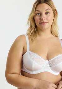 Hvid bh med bløde blonde detaljer langs toppen, justerbare stropper og glat stof. Designet med en støttende, struktureret form.