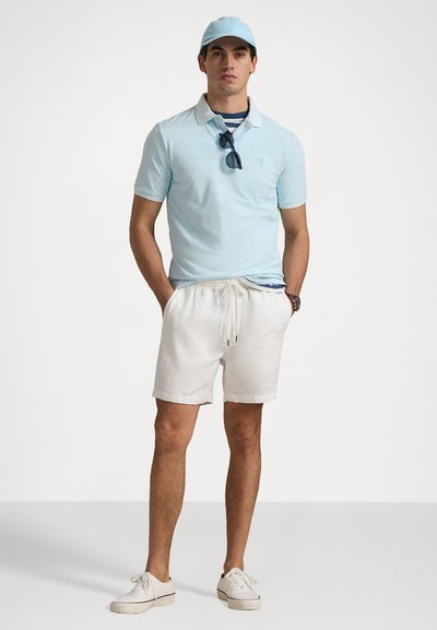 Tricou polo albastru deschis, pantaloni scurți albi cu șnur și adidași albi; asortat cu o șapcă potrivită și ochelari de soare pe un maieu cu dungi bleumarin.