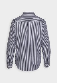 Navy and white vertically striped long-sleeve shirt with a buttoned collar, rounded hem, and featuring button accents at the cuffs.