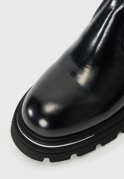 Botină din piele neagră până la gleznă, cu un finisaj lucios, vârf rotund și talpă din cauciuc cu un model distinct de profil și o linie albă de accent.