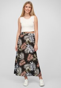 Svart maxiskjørt med et tropisk bladmønster i grønt, rosa og hvitt. Kombinert med en hvit cropped tanktop og hvite sneakers.