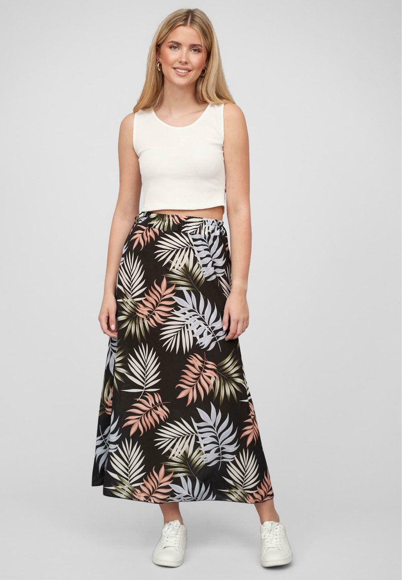 Svart maxiskjørt med et tropisk bladmønster i grønt, rosa og hvitt. Kombinert med en hvit cropped tanktop og hvite sneakers.