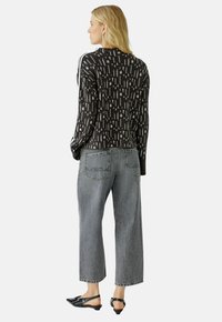 Zwart-witte gemusterde lange mouw top, grijze wijde jeans en zwarte slingback schoenen, die een relaxte pasvorm en gestructureerde stof tonen.