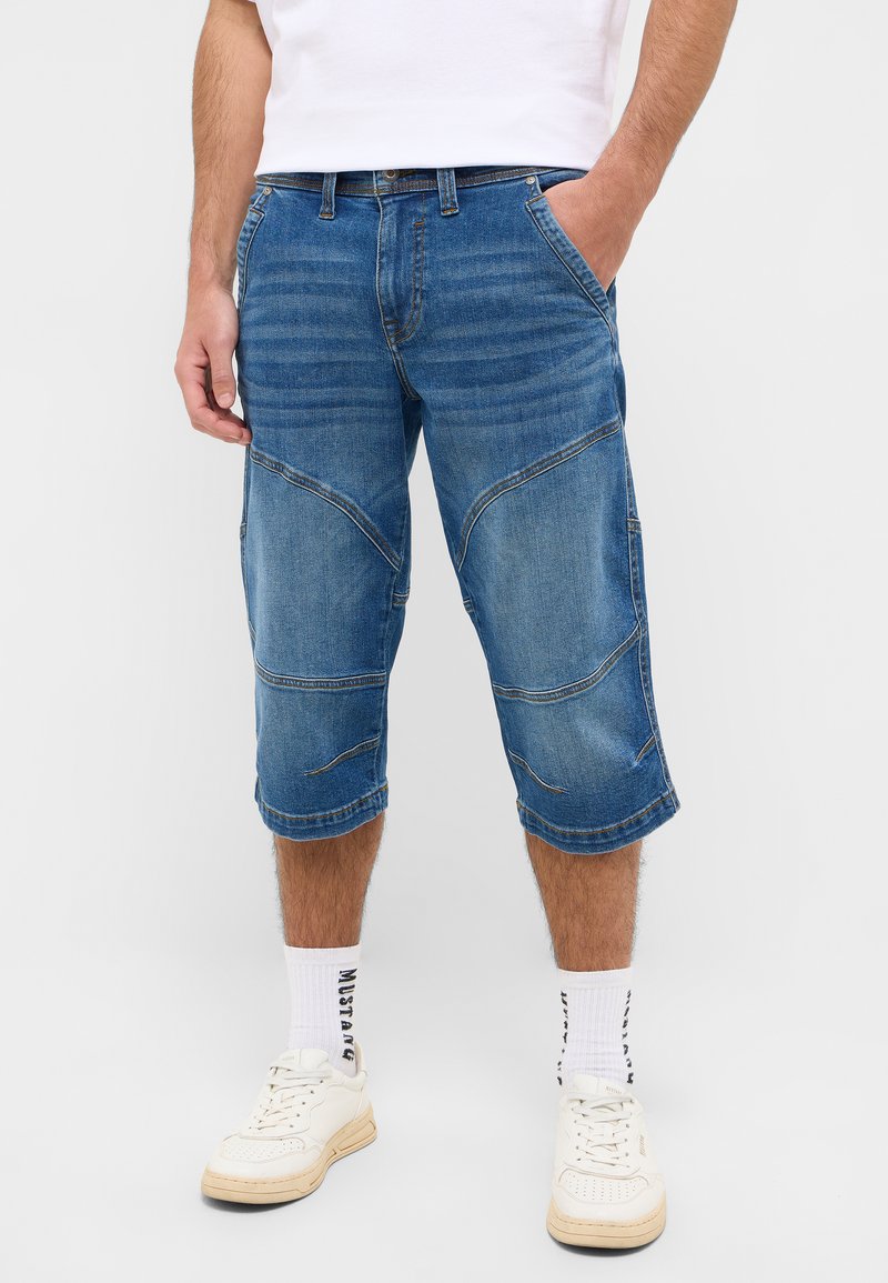Denim-Shorts in Mittelblau, knielang mit sichtbaren Nahtdetails und lockerer Passform. Mit Fronttaschen und einem Taillenbund ausgestattet.