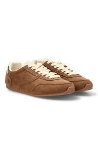 Zapatillas de ante marrón con cordones crema. Diseño de perfil bajo, superficie texturizada y suela de goma con un patrón de cala sencillo.
